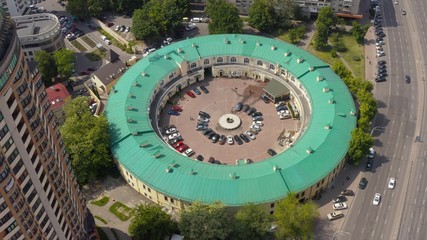 interesting round shape of the building with a green roof, view from the drone, smooth cinematic movement of the drone