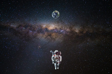 Astronaut in outer space over of the Earth with sun light. City lights on planet. Elements of this...
