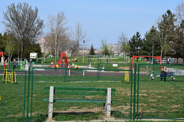 Fototapeta na wymiar Children's play and exercise equipment, in Belgrade park with green fence