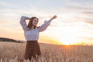 happy woman get high in field of wheat. sunset sky