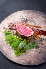 Gebratenes dry aged Rinderfilet Medaillon Steak natur mit Salat und Gewürzen als closeup auf einem Modern Design Teller