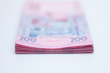 A lot of new banknotes in denominations of 200 Ukrainian hryvnias isolated on a white background with shadow. European money exchange. Ukraine currency. Selective focus