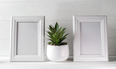 two photo frames on a white wooden shelf. White on white.