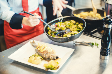 Head chef in restaurant putting food on a dish soon to be served