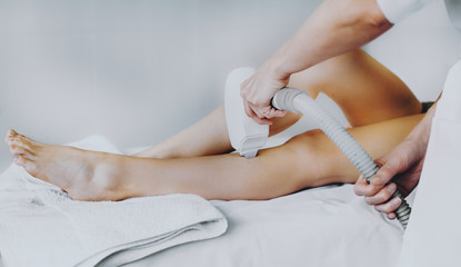 Fototapeta na wymiar Laser epilation procedure on the client's legs done at the spa salon