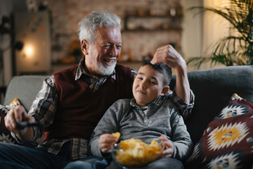 Grandfather and grandson watching television. Grandfather and grandson enjoying at home.