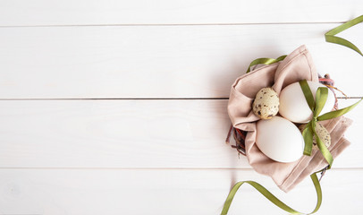 Eco style easter composition on white wooden background. Eggs with green ribbon and paper rabbit. Space for text. Flatlay 