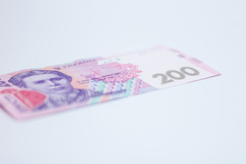 A lot of new banknotes in denominations of 200 Ukrainian hryvnias isolated on a white background with shadow. European money exchange. Ukraine currency. Selective focus
