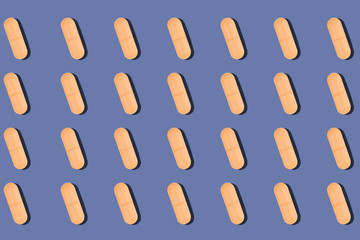 Pattern of orange pills with shadow on purple background