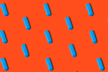 Seamless pattern with blue pills on orange background.