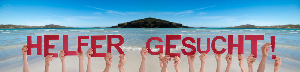 People Hands Holding Colorful German Word Helfer Gesucht Means Help Wanted. Ocean And Beach As Background