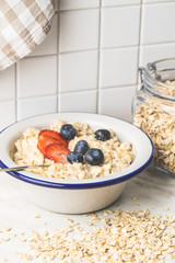 Bowl of oatmeal porridge with strawberries and blueberries.