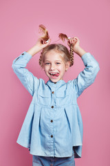 Funny little girl holding her pigtails and sticking tongue
