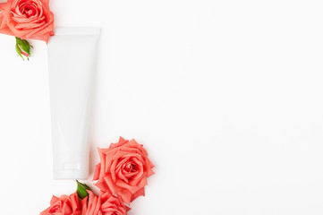 White unbranded cosmetics tube with roses. Cosmetology container for facial or hand cream, moisturizing lotion on light backdrop. Copy space in right side. Natural and eco-friendly cosmetic products