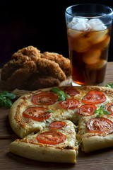 pizza Margarita with a glass of Cola and chicken wings on a wooden background