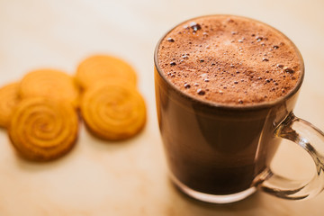 Chocolate coffee with foam in a glass mug on a light background. Tasty, energizing Breakfast.