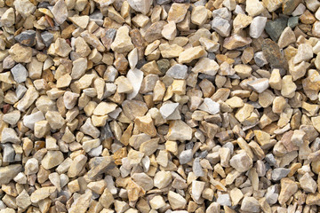 Photo of rubble and gravel on the ground. Texture brown, yellow and gray stones. Image of broken stones and gravel