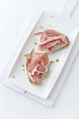 Sandwich with soft cheese and ham. Bright wooden background.	