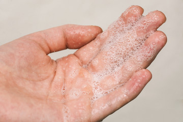 Hand in foam close up. Hand washing with soap. Cleansing the skin of dirt, germs and viruses. Protecting health from flu and dangerous diseases.