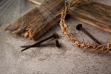 Easter background depicting the crucifixion with a rustic wooden cross, crown of thorns and nails.