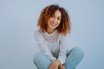 African american millennial woman sitting on the floor. Young female with urban clothes isolated on white background with horizontal copyspace. Afro culture youth concept indoors.