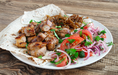 shashlik with fried onion on flatbread with salad
