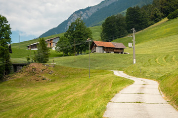 Path Going up to a hill and blue Sky with Clouds. Wooden houses in the background