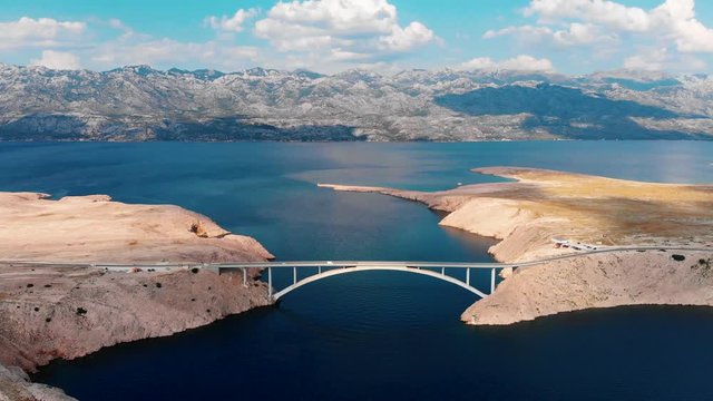 Aerial, drone video of Paski bridge and beautiful landscapes on island of Pag in Croatia showing cars passing by blue waters of Adriatic Sea 