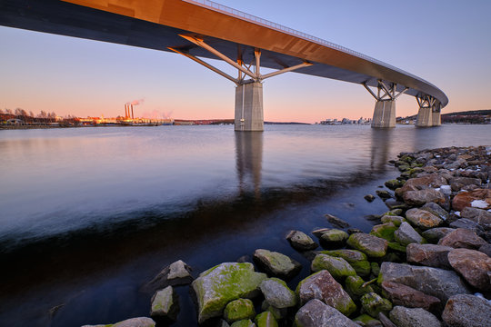 Big bridge going over a cove with stones foreground and a city in the background
