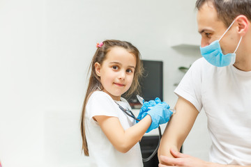 Fototapeta premium Adorable little girl and her father or doctor in medical mask by the window at home or hospital. . Quarantine. Coronavirus. Epidemic.