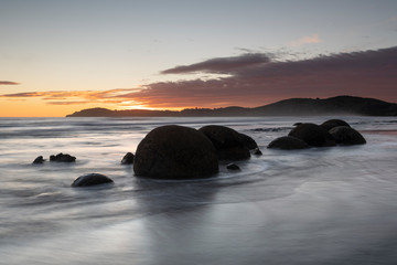 Fototapeta na wymiar Moeraki Boulders at sunrise with a colourful sky, New Zealand