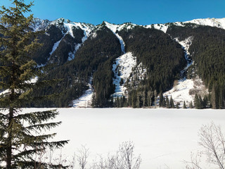 A view of the snow covered mountains and frozen river on Lillooet Lake Road in Squamish-Lillooet C, BC, Canada.
