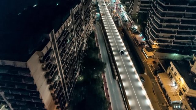 Aerial reveal shot of Monaco Monte Carlo skyline city center street car driving at night