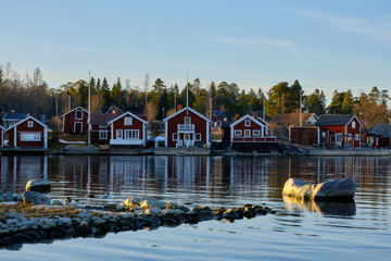 Small red houses by the sea with stones in the foreground