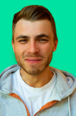 Fototapeta premium young hipster with a beard is smiling and looking at the camera on a neo mint color wall background.