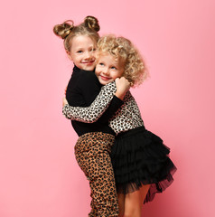 Laughing kids girls friends sisters in leopard print clothes pants and sweater are running jumping hugging hold hands together