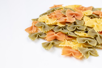 Pile of raw colored pasta with bow shape on the grey marble table background