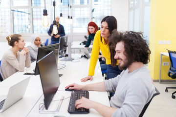 Group of multiethnic colleagues working on desktop computers in a modern office space.