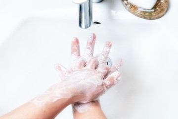 Washing hands with soap under the faucet with water