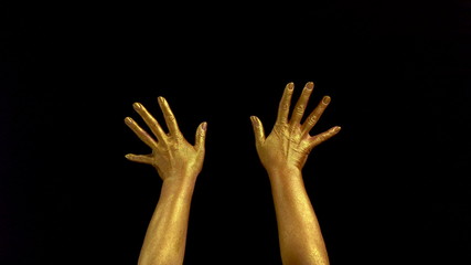 Nice footage of woman gold hands gesture. Black background. Hands in gold color paint on black...
