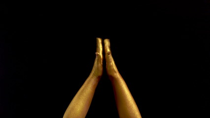 Nice footage of woman gold hands gesture. Black background. Hands in gold color paint on black background.