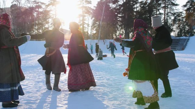Russian folk - men and women in Russian folk costumes are dancing in pairs in a winter park