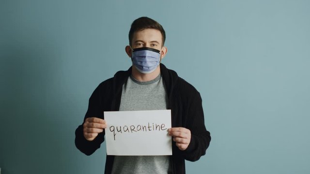Young man in protective mask is holding a poster, urging others to stay in quarantine during the coronavirus outbreak and be responsible, protecting your life and lives of others.