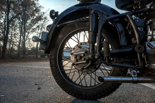 Rear wheels of an old Soviet motorcycleK750. Close-up. Black motorcycle on the asphalt in the afternoon.
