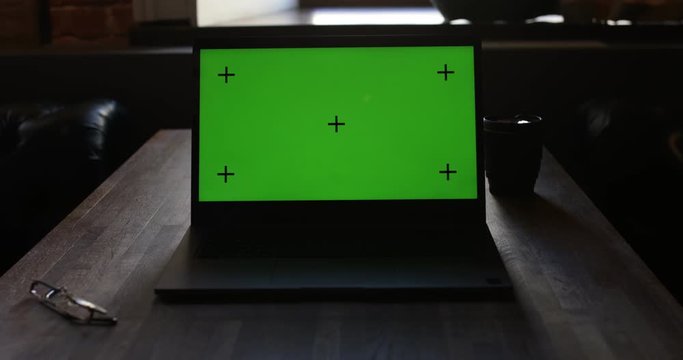 Laptop With Green Screen and Tracking Dot. Dark office. A Man's Hand Opens The Laptop Screen