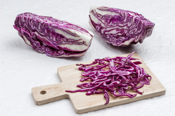 Halved red cabbage, sliced cabbage on cutting board.