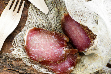jerky in gauze on a wooden table, next to a wooden knife and fork. homemade organic food and...
