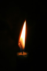 Flame of a candle burning in the dark