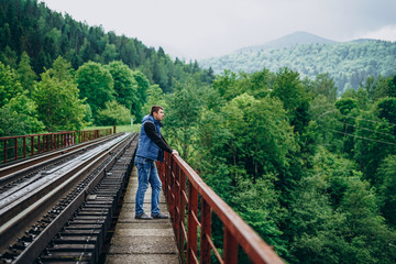 Fototapeta na wymiar Young man on railway track on forest background. The observation deck.