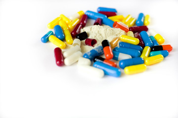many multi-colored medical capsules and white powder, substance, on a white background, side view, close up, isolate